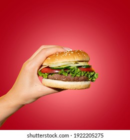 Hand Holding A Burger In A Hot Red Background. Eating And Healthy Concept, Restaurant Food Concept.