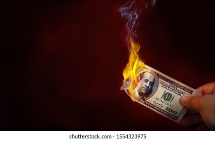 Hand Holding A Burning 100 Dollar Bill Money With Copy Space.