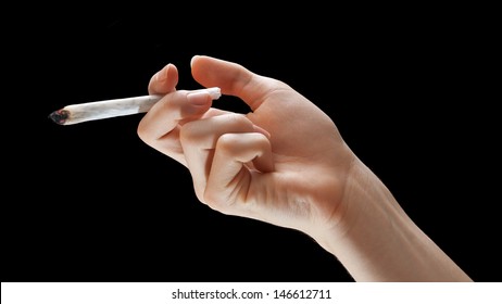 Hand holding burning joint isolated on black background