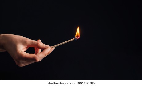 Hand holding a burning match, isolated on black background