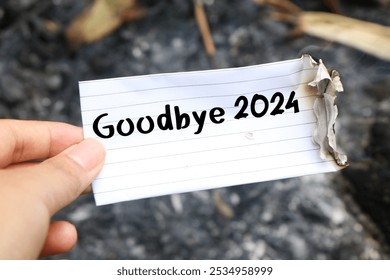 Hand holding burning paper on fire and pile of paper waste with Goodbye 2024 written on it. new life and new year 2025 concept. 2024 paper is burning, say goodbye to 2024 - Powered by Shutterstock