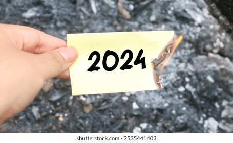 Hand holding burning paper on fire and pile of paper waste with 2024 written on it. new life and new year 2025 concept. 2024 paper is burning, say goodbye to 2024 - Powered by Shutterstock