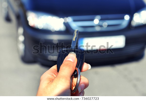 Hand holding\
button on the remote car.\
In selective focus of woman hand presses\
on the remote control car alarm systems..Auto insurance\
business.Car security lock system\
concept.
