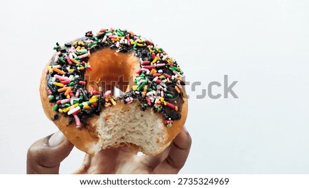 A hand holding a byte of donut that with chocolate.