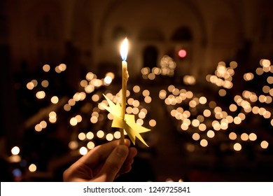 Hand Holding A Candle In Church During Christmas Christian Mass.