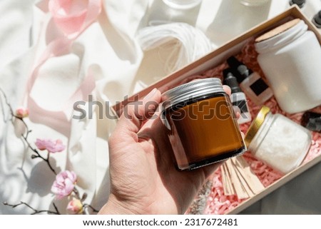 hand holding candle DIY gift box with soy wax, candle, wickes and essential oil for candle crafting. Hobbies and small business. Mockup