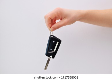 A Hand Holding A Car Key On A White Background.