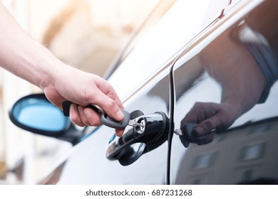 Hand holding a car key and opening the car door lock - Shutterstock ID 687231268