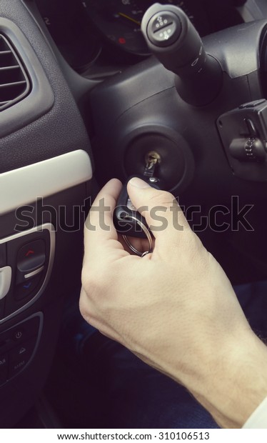 Hand holding car key for starting the\
car.Male hand with car key on car background\
