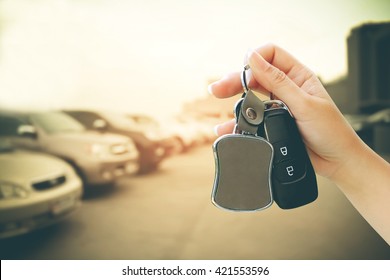 Hand Holding Car Key And Tag With Blur Terrace Car Park Background