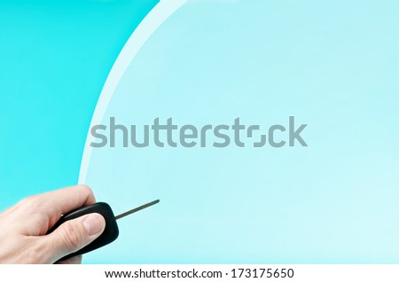 Hand holding car keys on blue background