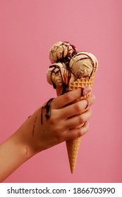A Hand Holding Caramel Ice Cream With Drizzled Chocolate Sauce