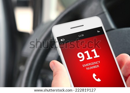 hand holding cellphone with emergency number 911 in car