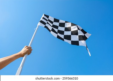 Hand Holding Checkered Flag On Blue Sky Background