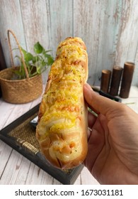 A Hand Holding Cheese Stick Over The Wooden Background