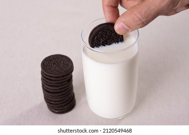 Hand Holding Chocolate Cream Cookies Dunk To Glass Of Milk.