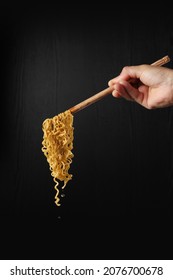 Hand Holding Chopsticks And Noodles Isolated On Black Background