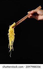 Hand Holding Chopsticks And Noodles Isolated On Black Background