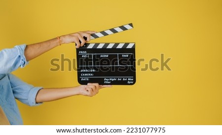 Hand is holding clapper board or clapperboard or movie slate, used in film production and cinema ,movies industry isolated over color background.