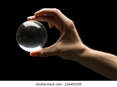 Hand Holding A Clear Transparent Crystal Glass Ball Isolated On Black Background