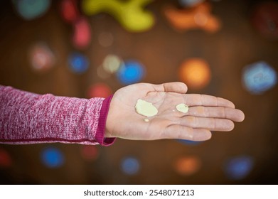 Hand holding climbing chalk against a colorful rock climbing wall during a training session in an indoor climbing gym - Powered by Shutterstock