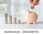 Hand holding coin in saving piggy bank with coins stack in graph for save or money savings plan safety and growth or investment planning.