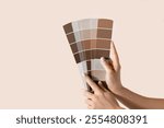 Hand holding Color samples palette design catalog. New trending PANTONE 17-1230 Mocha Mousse colour of 2025 year 
