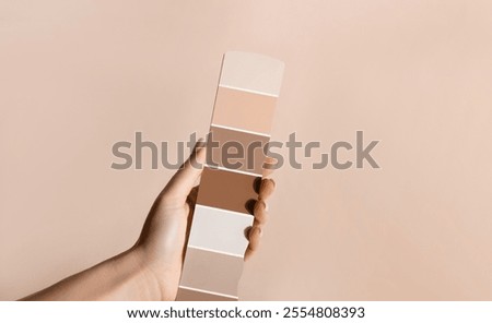 Hand holding Color samples palette design catalog. New trending PANTONE 17-1230 Mocha Mousse colour of 2025 year 
