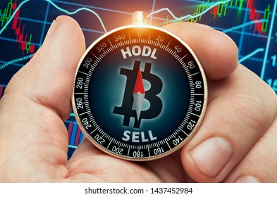 hand holding compass with glowing bitcoin symbol in front of stock market chart data. Compass needle showing HODL word. 
