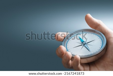 Hand holding a compass over blue background with copy space. Concept of Strategic orientation in business or marketing. Composite image between a 3d illustration and a photography.
