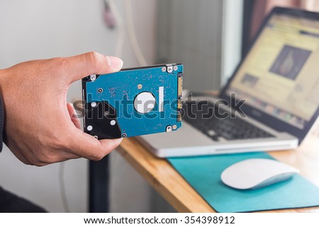 Hand holding Computer Harddisk with office background and vintage effect.