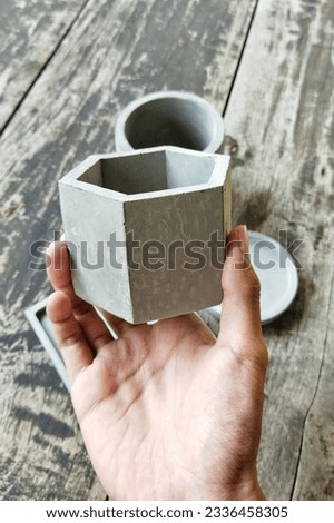 hand holding a concrete hexagon pot with blur background