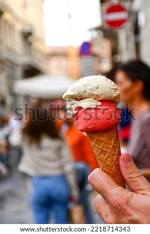 Hand holding cone with  colorful delicious  traditional Italian Gelato ice-cream in  Bologna  in Northern Italy in summer day