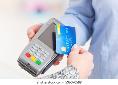 Hand Holding Contactless Credit Or Debit Card Over Wireless Payment Terminal At Shop