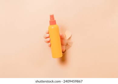 Hand holding a cosmetic spray container (for skin or hair). Cosmetic beauty packaging