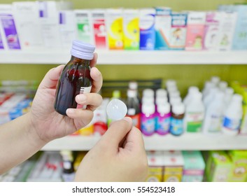 Hand Holding A Cough Syrup Bottle In Pharmacy Drugstore.