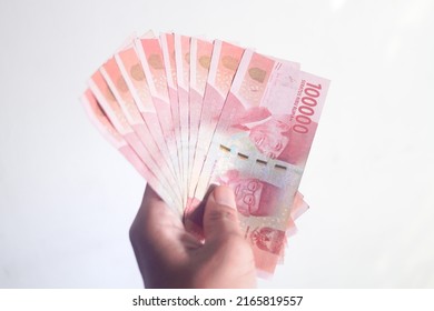 Hand holding and counting Indonesean Rupiah (IDR) bank notes with white background - Shutterstock ID 2165819557