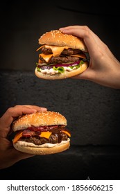 Hand Holding A Craft Beef Burger With Cheese On Rustic Background