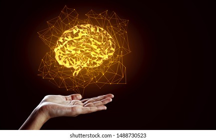 Hand holding creative glowing polygonal brain on dark background. AI and future concept