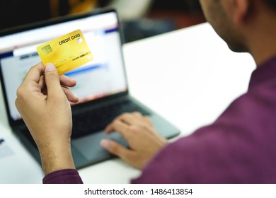 Hand holding credit card, typing on the keyboard of laptop, online shopping and electronic payments concept.   