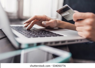 Hand holding credit card and using laptop. Businesswoman or entrepreneur working from home. Online shopping, e-commerce, internet banking, spending money, work from home concept