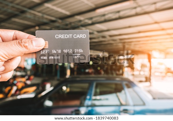Hand holding\
a  credit cards at auto repair\
shop
