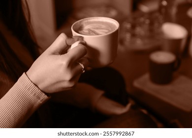 A hand holding a cup of coffee frames the earthy aesthetic. 2025 Color of the Year Mocha Mousse inspired design featuring a warm coffee-brown tone. - Powered by Shutterstock