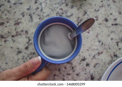 Hand holding a Cup of coffee with a spoon