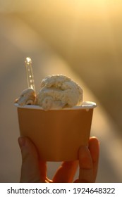 Hand Holding A Cup Of Ice Cream At Sunset. Selective Focus.