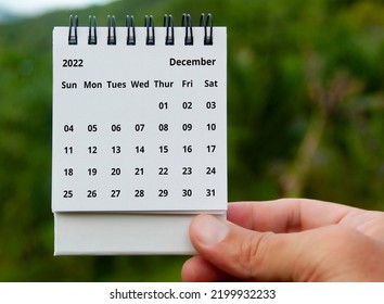 Hand holding December 2022 calendar with copy space and nature background. - Shutterstock ID 2199932233