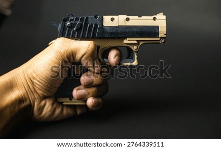Hand Holding Desert Eagle Model Toy Gun Isolated on Black Background