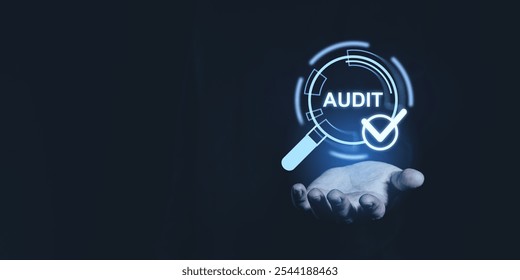 A hand holding a digital audit icon with a magnifying glass and checkmark on a dark background. Represents quality assurance and approval - Powered by Shutterstock