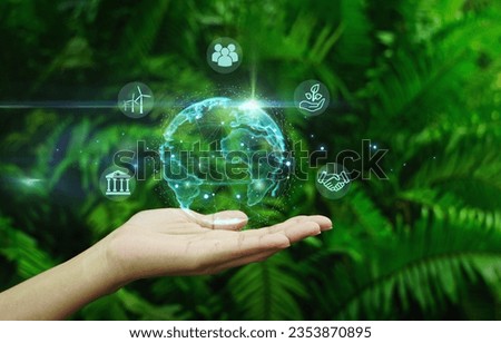 Hand holding digital earth globe with ESG smart icon around it on green natural leaf background.Business cooperation for a sustainable environment.ESG environment social governance concept.