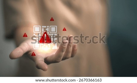 Hand holding digital QR code with warning alert sign, concept of QR code scam, cyber fraud, phishing attack, online security risk and mobile payment vulnerability.